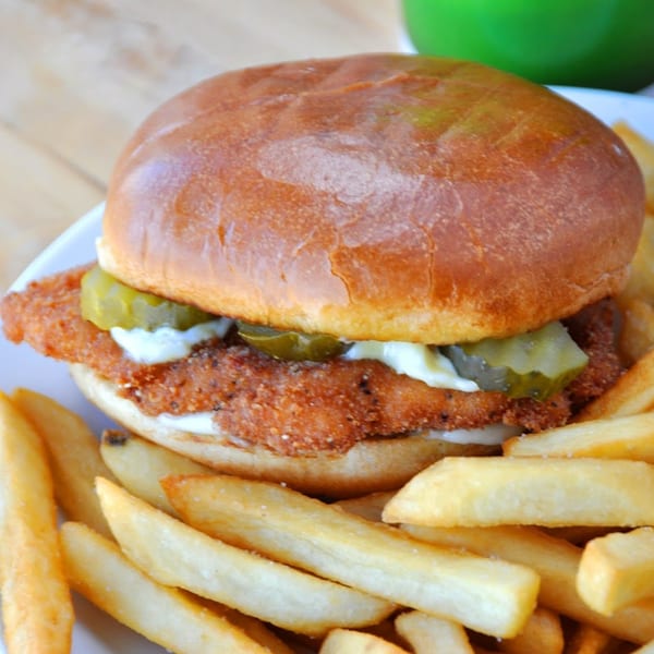 The Bird's fried chicken sandwich with pickles and mayonnaise, served with a side of fries.