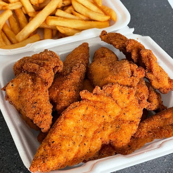 Crispy fried chicken tenders and golden french fries in white takeout containers from The Bird.