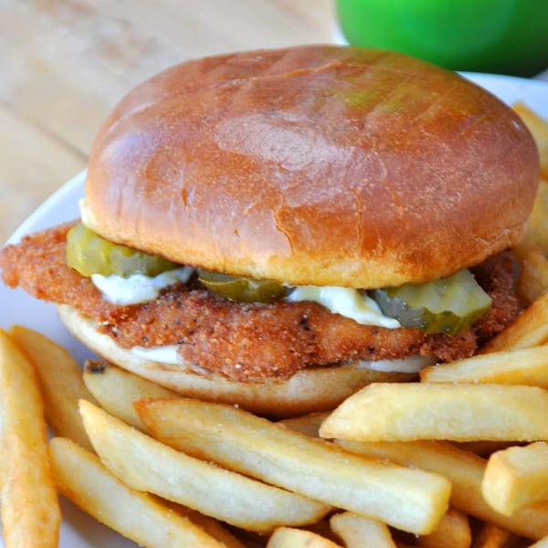 The Bird's fried chicken sandwich with pickles and mayonnaise, served with a side of fries.