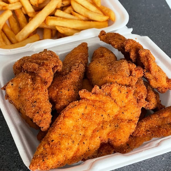 Crispy fried chicken tenders and golden french fries in white takeout containers from The Bird.