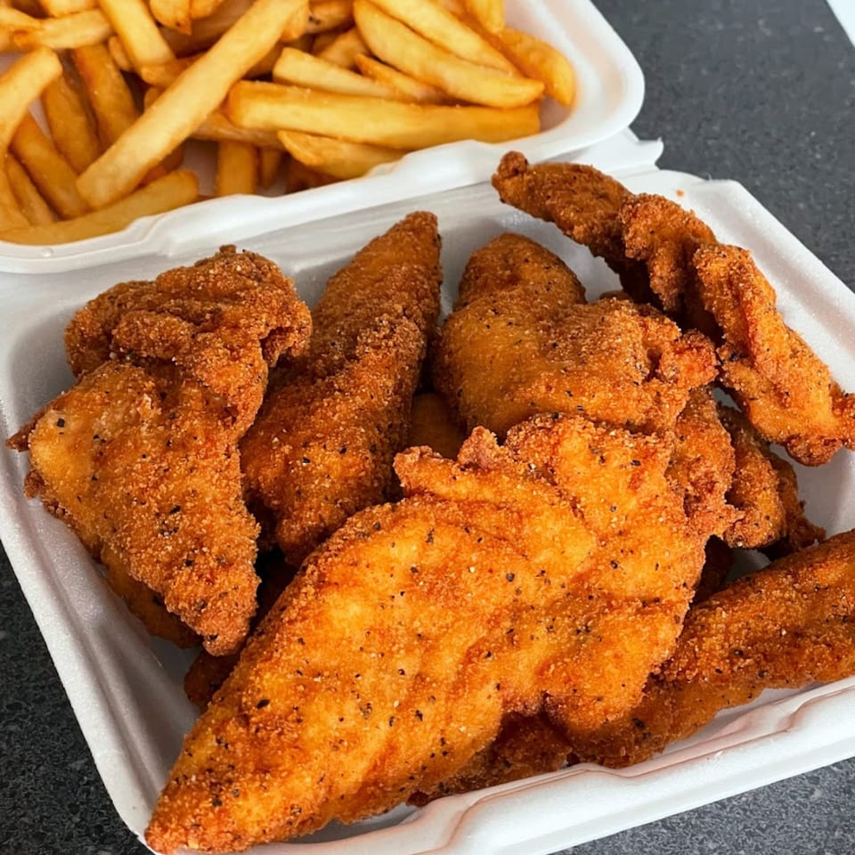 Crispy fried chicken tenders and golden french fries in white takeout containers from The Bird.