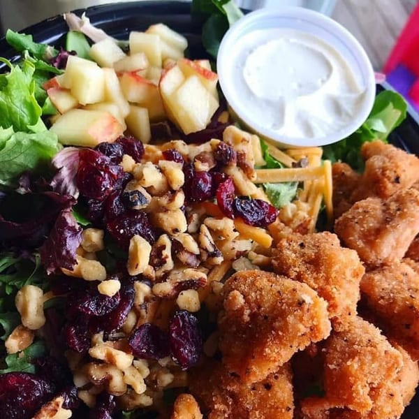 The Bird's fried chicken nuggets with a side salad of greens, apples, cranberries, and walnuts.