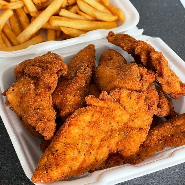 Crispy fried chicken tenders and golden french fries in white takeout containers from The Bird.